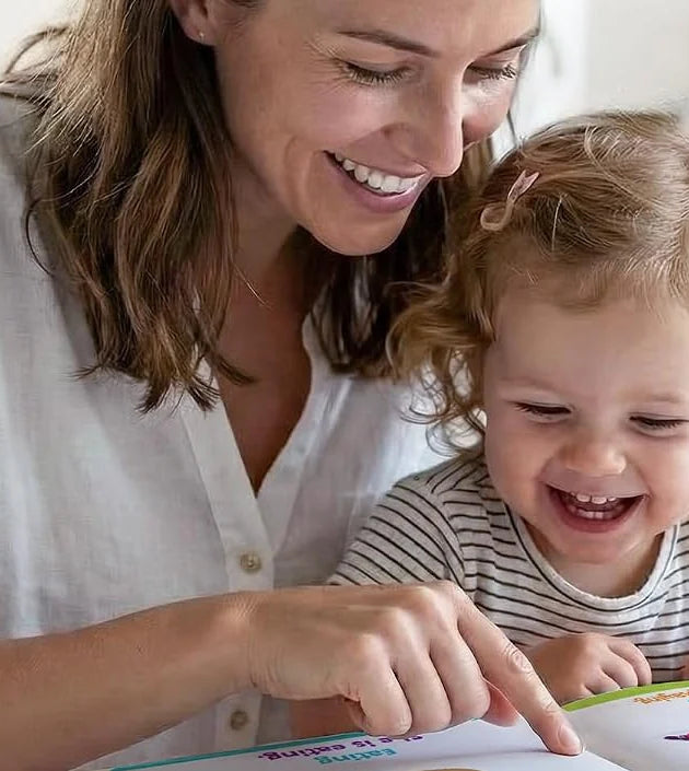 A parent and toddler laughing over a book